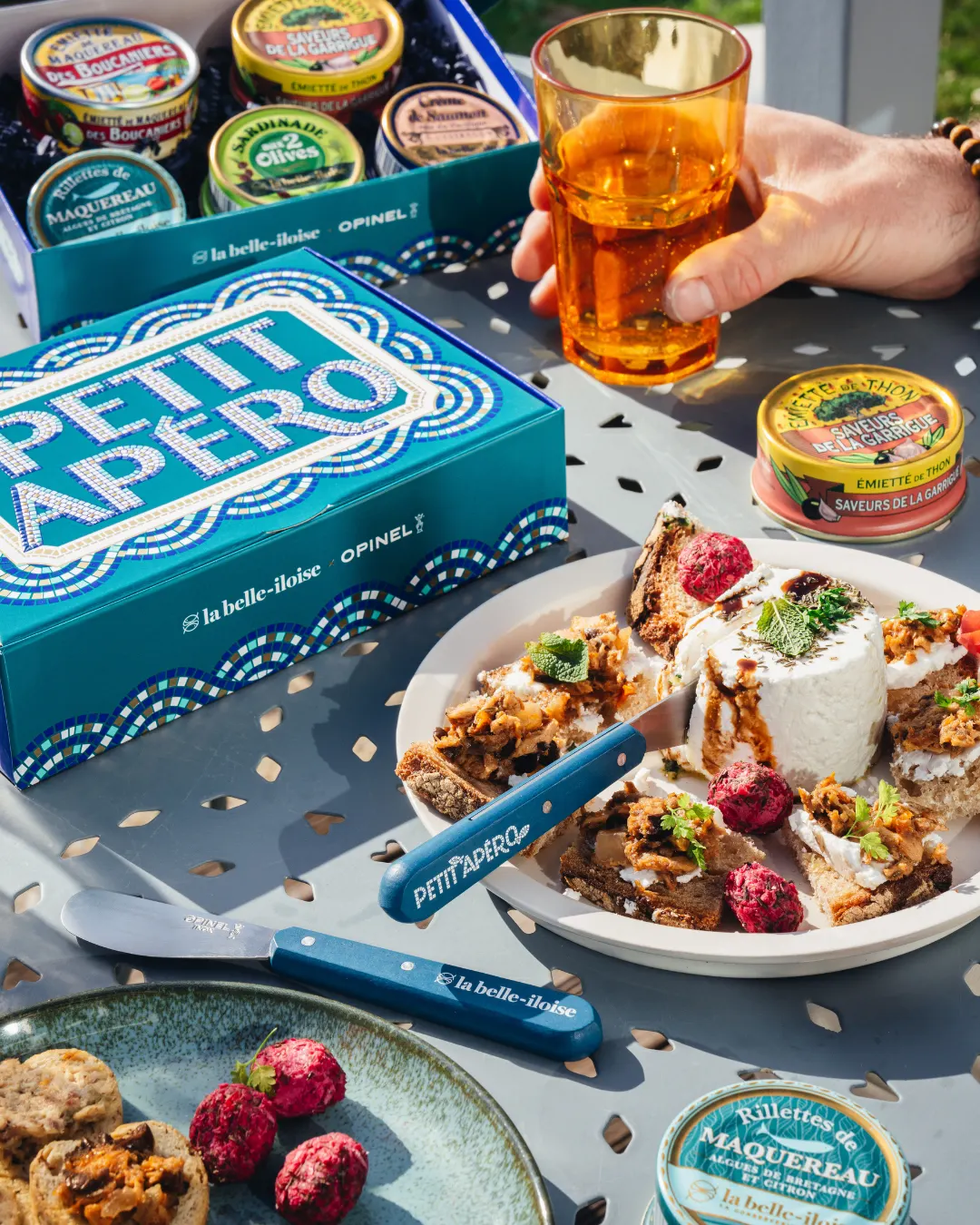 Visuel publicitaire Meta réalisé par AGAT pour la belle-iloise : le coffret Petit Apéro x Opinel en situation d'apéritif estival, campagne de printemps 2026