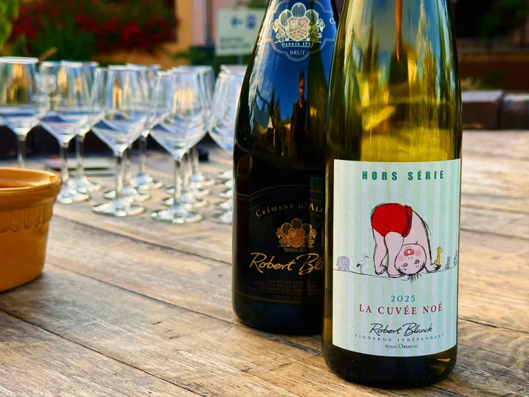 Bouteille de la cuvée Noé du domaine Blanck et verres alignés sur une table en bois